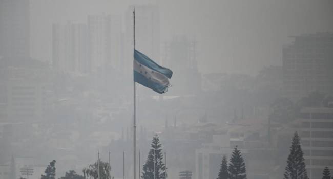 Una bandera nacional hondureña ondea en medio de una densa capa de humo que cubre Tegucigalpa en mayo de 2024.