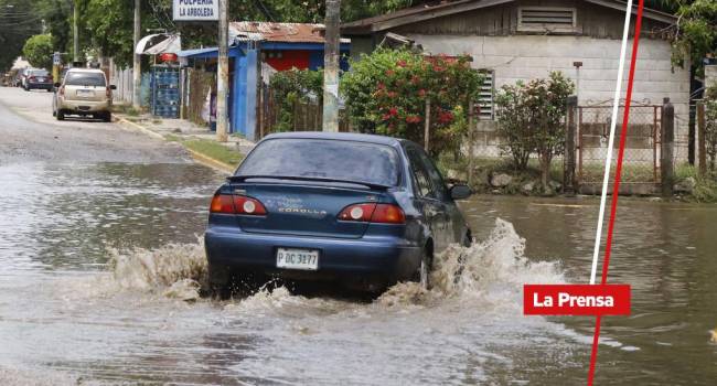 Vehículo turismo avanza por una calle inundada por las lluvias | Fotografía de archivo
