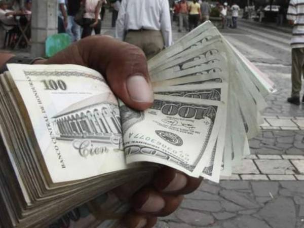 Lempiras y dólares en la mano de un cambista en centro de Tegucigalpa.