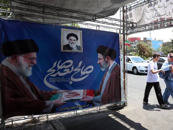 Iraníes pasan junto a un cartel del difunto líder supremo iraní Alí Jameneí (I) junto a su hijo y sucesor, Mojtaba Jameneí, en Teherán, Irán, el 11 de junio de 2026. EFE/EPA/ABEDIN TAHERKENAREH