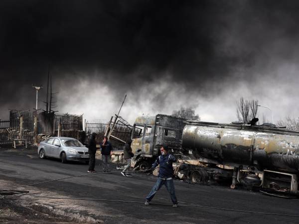 Los trabajadores observan cómo el humo sigue elevándose desde la refinería de petróleo de Shahran tras el ataque aéreo de anoche en Teherán, Irán. EFE/EPA/ABEDIN TAHERKENAREH