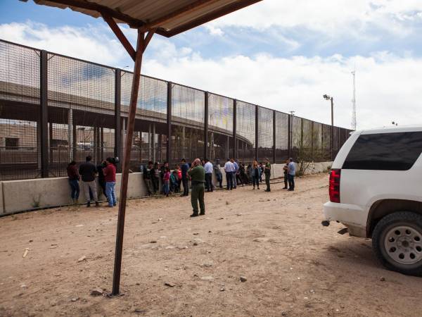 Un grupo de 22 migrantes de Honduras, Guatemala y Salvador detenidos para su procesamiento debajo del Puente Paso Del Norte esperan ser transportados el 28 de marzo de 2019 en El Paso, Texas.