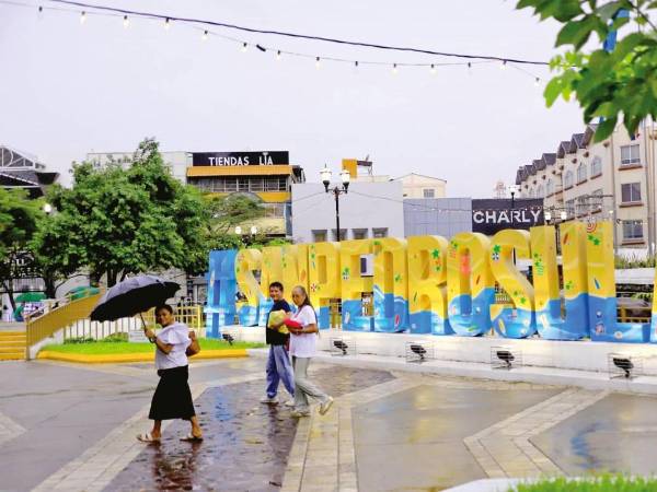 Hondureños caminan bajo la lluvia en San Pedro Sula | Fotografía de archivo