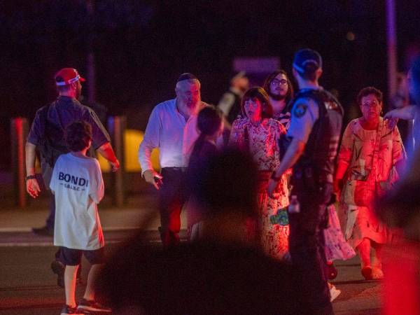 Un oficial de policía observa a la gente que desaloja la playa de Bondi en Sídney, Australia, tras el ataque terrorista ocurrido este domingo.