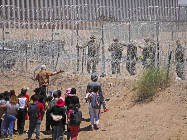 Un grupo de migrantes habla con agentes de la Guardia Nacional de Texas en la frontera entre EEUU y México.