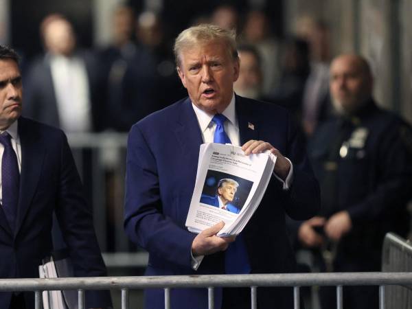 Trump muestra recortes de prensa a la salida de una audiencia en un tribunal de Nueva York.