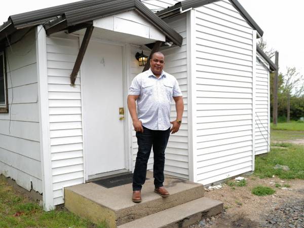 El cubano Israel Gómez Estrada posa frente a su casa en Nebraska.