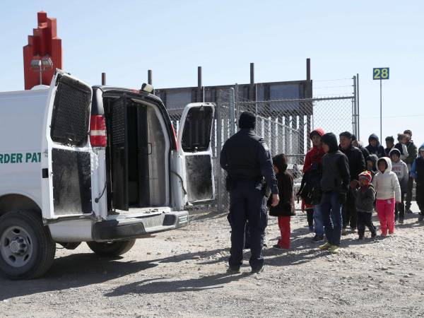 Un agente de la Patrulla Fronteriza de Estados Unidos carga a migrantes detenidos en una camioneta en la frontera de Estados Unidos y México.