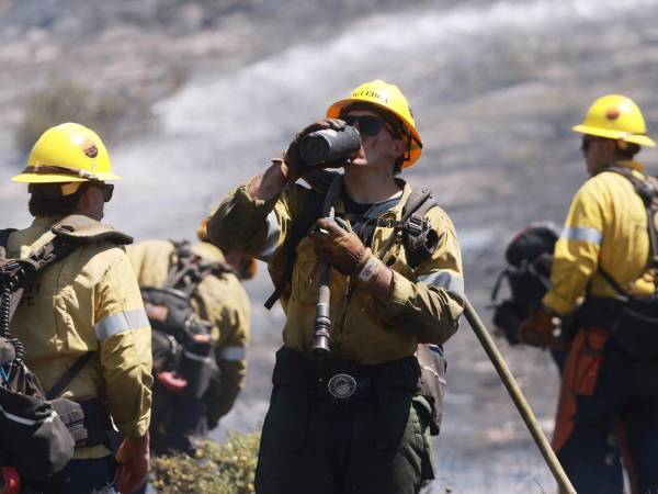 Bomberos de Los Ángeles se hidratan mientras combaten fuegos forestales.