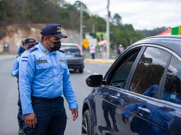 Policía de tránsito solicita revisión a conductores en una parada de tránsito.