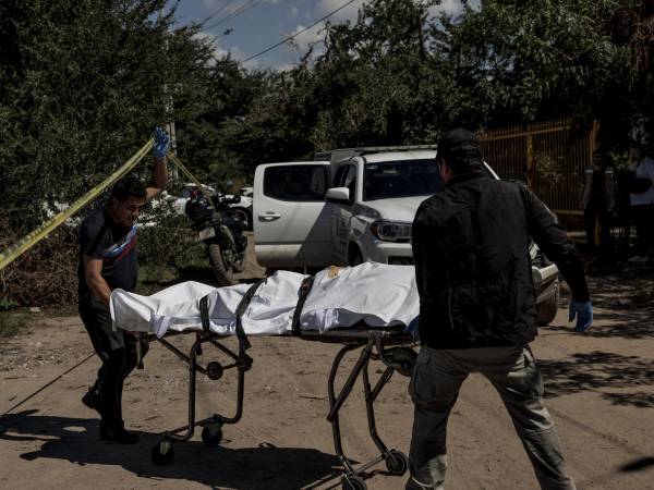 Un trabajador funerario (izq.) ayuda a recuperar un cuerpo en las afueras de la ciudad de Culiacán, México.