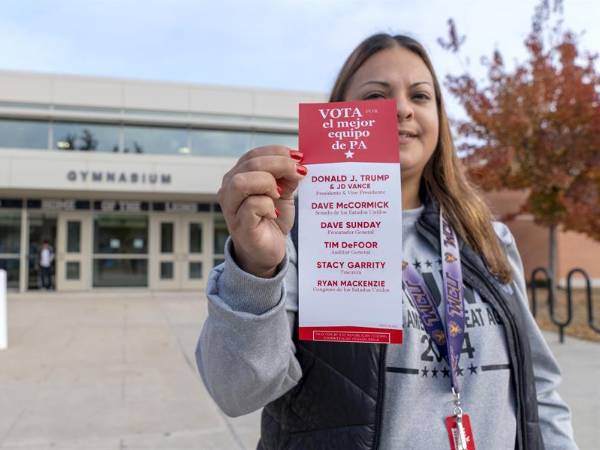 La voluntaria republicana Jackie Rivera, enseña un folleto con los nombres de todos los candidatos republicanos a la entrada de un centro de votación.
