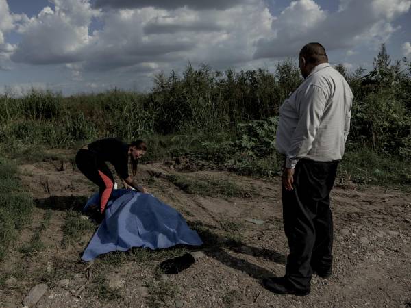 Juani Andrade cubre el cuerpo de su primo José Carlos Sazueta con una tela proporcionada por Ramón Soto (der.), un trabajador funerario de Culiacán, Sinaloa.