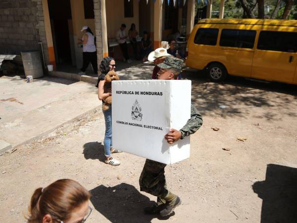 Un militar hondureño carga una maleta electoral en elecciones primarias.