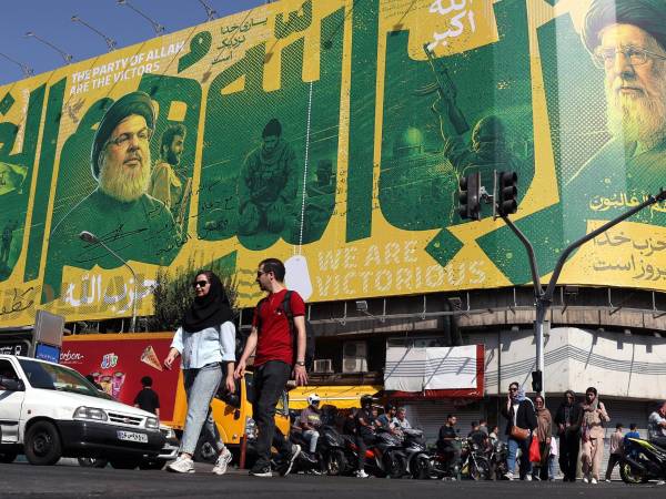 Iraníes transitan ante una valla publicitaria en Teherán que representa al exlíder de Hizbulá, Hasán Nasrala (i) y al difunto líder supremo iraní, Alí Jameneí (d). EFE/EPA/ABEDIN