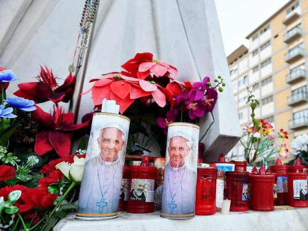 Flores y velas colocadas al pie de una estatua del papa San Juan Pablo II frente al Hospital Universitario Gemelli, donde el papa Francisco está ingresado, en Roma, el 21 de febrero de 2025. EFE/EPA/FABIO CIMAGLIA