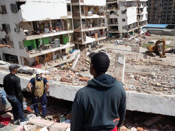 Personas observan edificios afectados por terremotos este jueves, en Catia La Mar (Venezuela). El presidente del Parlamento de Venezuela, el chavista Jorge Rodríguez, informó que los fallecidos por los dos terremotos ocurridos el miércoles en su país ya dejan 920 muertos y 3.360. EFE/ Ronald Peña R.