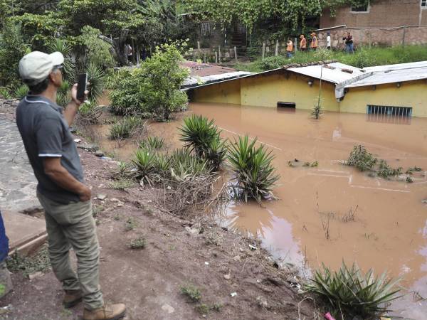 Un hombre toma una fotografía de casas afectadas por las lluvias hace dos semanas, en la aldea de Zarabanda, en el municipio de Santa Lucia (Honduras).