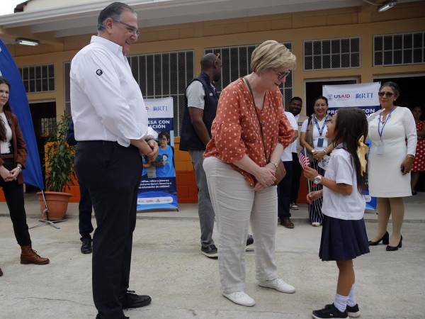 La embajadora de Estados Unidos en Honduras, Laura Dogu, saluda a una estudiante junto a Luis Átala, vicepresidente de Grupo Ficohsa (d), durante un evento en el Centro de Educación Básica Armando Montes en Juticalpa (Honduras).