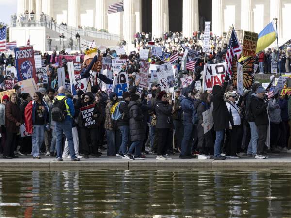 Activistas sostienen carteles y pancartas mientras participan en la marcha 'No Kings' (No reyes) en Washington.