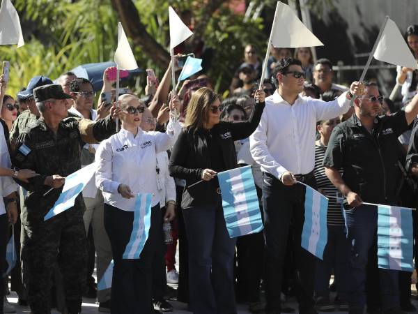 El jefe del Estado Mayor Conjunto de las Fuerzas Armadas de Honduras, el general Roosevelt Hernández (2-i), la consejera presidenta del Consejo Nacional Electoral (CNE), Ana Paola Hall (c), y el consejero del CNE Marlon Ochoa (2-d) sostienen banderas en el acto de la distribución del material electoral para las elecciones generales del 30 de noviembre este jueves, en Tegucigalpa (Honduras).