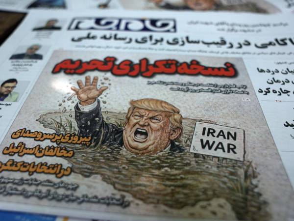 Copias del diario iraní 'Jame-Jam' con una caricatura del presidente de EE.UU., Donald Trump, y un titular en persa que dice 'Versión Duplicada de Sanciones' informando sobre la nueva amenaza económica contra Irán, junto a un quiosco en Teherán, Irán, el 22 de agosto de 2026.