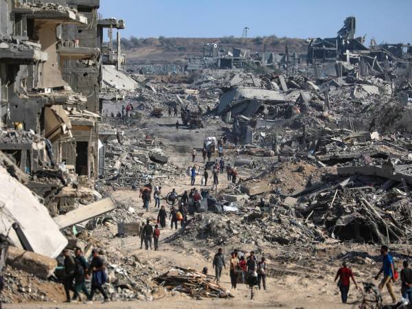 Foto del pasado día 11 de octubre en la que se ve a desplazados internos en Gaza caminando entre los escombros y los edificios destrozados de Ciudad de Gaza.