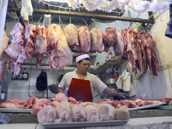 Tony Mena trabaja en su puesto de venta de carne en la feria del agricultor y el artesano el 22 de diciembre de 2025 en Tegucigalpa.