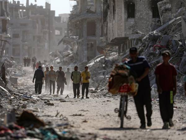 Imagen de archivo de palestinos caminando por una calle entre los escombros de los edificios destruidos en medio del alto el fuego entre Israel y Hamas.