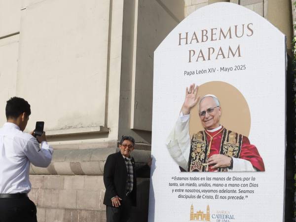 Personas se toman fotografías al lado de una imagen de León XIV en la catedral de Lima al día siguiente de su elección como papa.