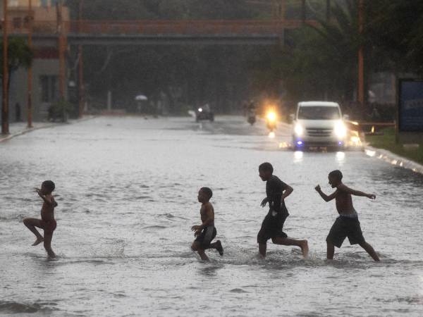 Un grupo de niños cruza por una calle inundada en Santo Domingo (República Dominicana).