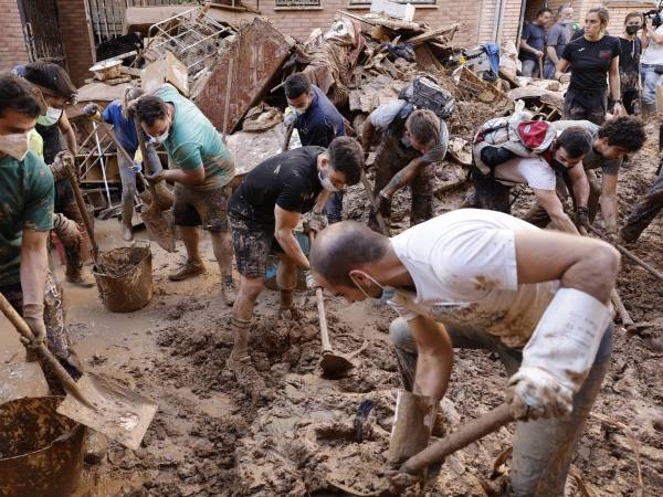 Varias personas retiran el lodo acumulado en una calle de la localidad valenciana de Paiporta, este sábado.