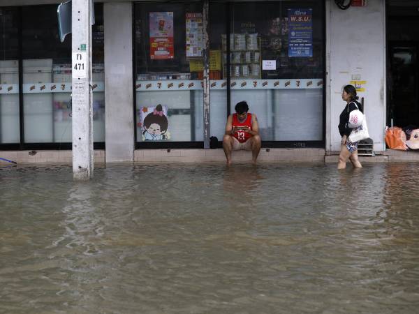 Un residente camina por el agua tras un aguacero prolongado en una comunidad anegada de Bangkok, cuyos 50 distritos fueron declarados zonas de desastre por inundaciones tras las lluvias intensas y prolongadas. EFE/EPA/RUNGROJ YONGRIT