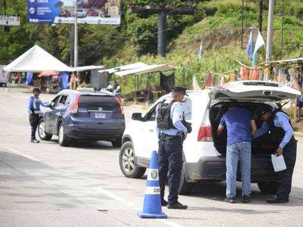 Agentes de la Policía Nacional inspeccionan vehículos en una de las salidas de San Pedro Sula.