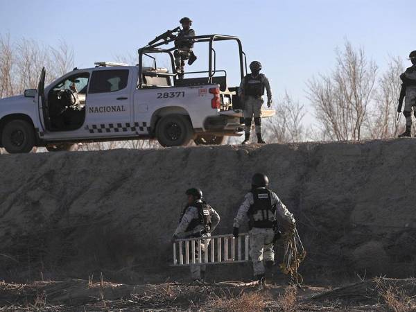 Agentes de la Guardia Nacional mexicana retiran las escaleras que usan los traficantes de personas para escalar el muro con EEUU.