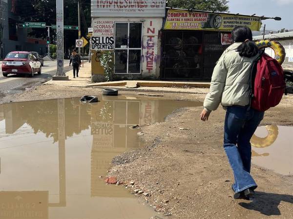 Personas caminan entre agua estancada en una calle, este viernes en Oaxaca, México.