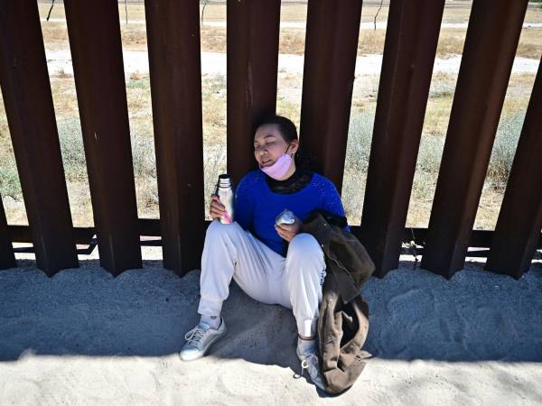 Un migrante descansa junto al muro en Arizona en medio de altas temperaturas por el inicio del verano en EEUU.