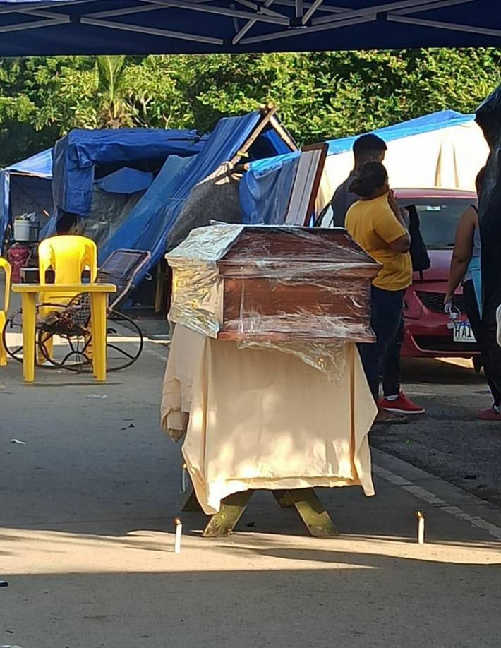 Sin velas, sin cruz y sin flores, solo un mantel debajo del ataúd.