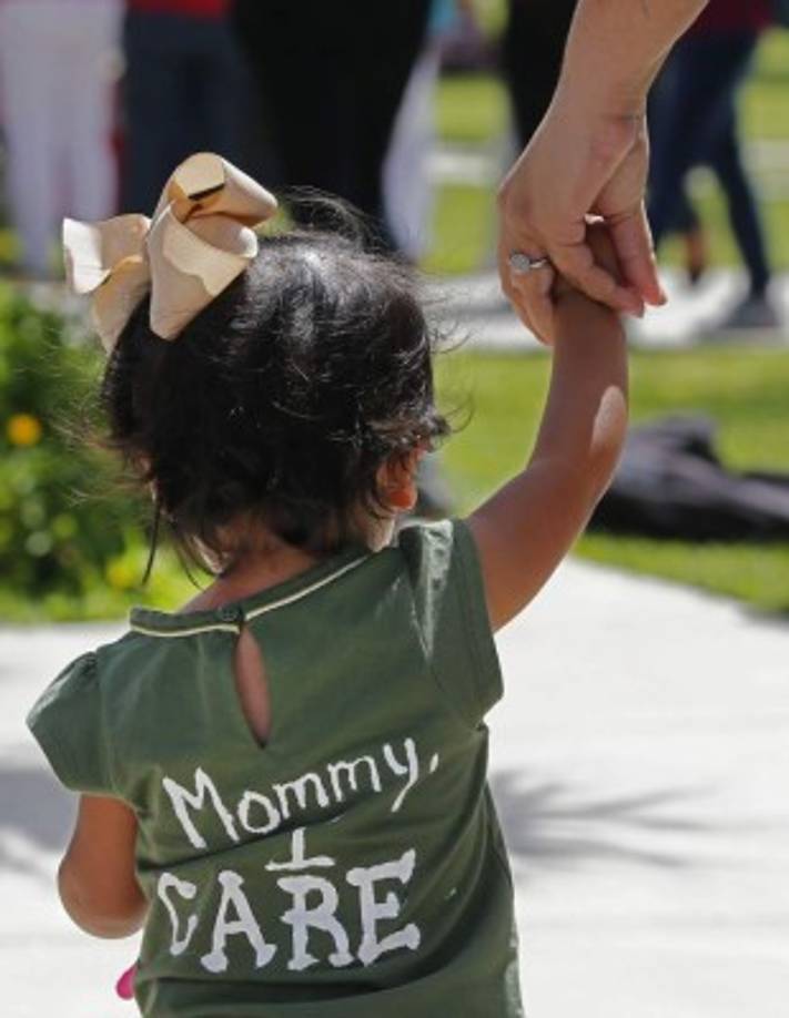 Una mujer camina con su hija pequeña durante una manifestación convocada por la Unión Americana de Libertades Civiles (ACLU) frente a la Corte Federal de Brownsville para protestar contra la política de inmigración 'cero tolerancia' de la administración del presidente Trump en Brownsville, Texas.