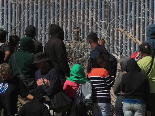 Migrantes esperan entre los alambres de púas mientras un agente estadounidense en Ciudad Juárez, Chihuahua, México.