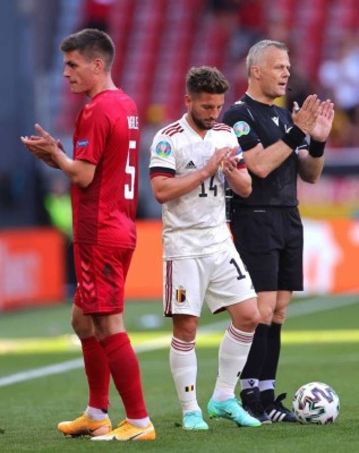 El danés Joakim Maehle, el belga Dries Mertens y el árbitro alemán Bjorn Kuipers aplaunden en el minuto 10 en homenaje a Eriksen. <br/><br/>Foto EFE
