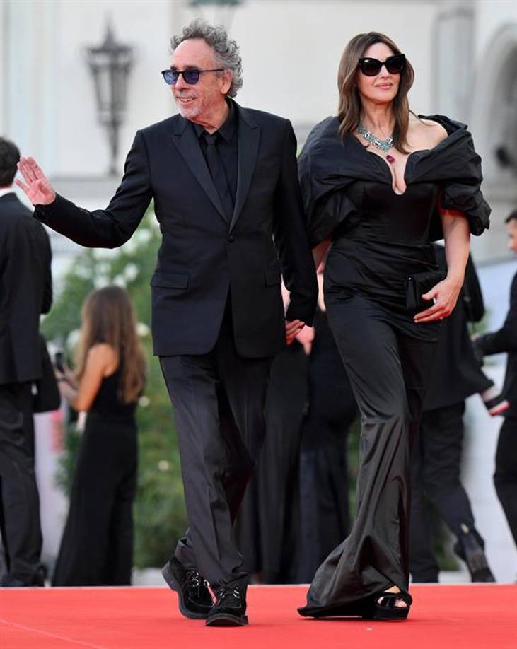 El cineasta Tim Burton y la actriz Monica Bellucci, su pareja, protagonizaron este miércoles la primera alfombra roja del Festival de Venecia por el estreno de su película ‘Beetlejuice, Beetlejuice’ junto al resto del reparto. El realizador y la italiana desataron la locura al llegar de la mano a la alfombra roja, para después posar por separado. Ella, con gafas de sol y un largo vestido negro con estola abullonada, se acercó a firmar algunos autógrafos entre el público que la aclamaba