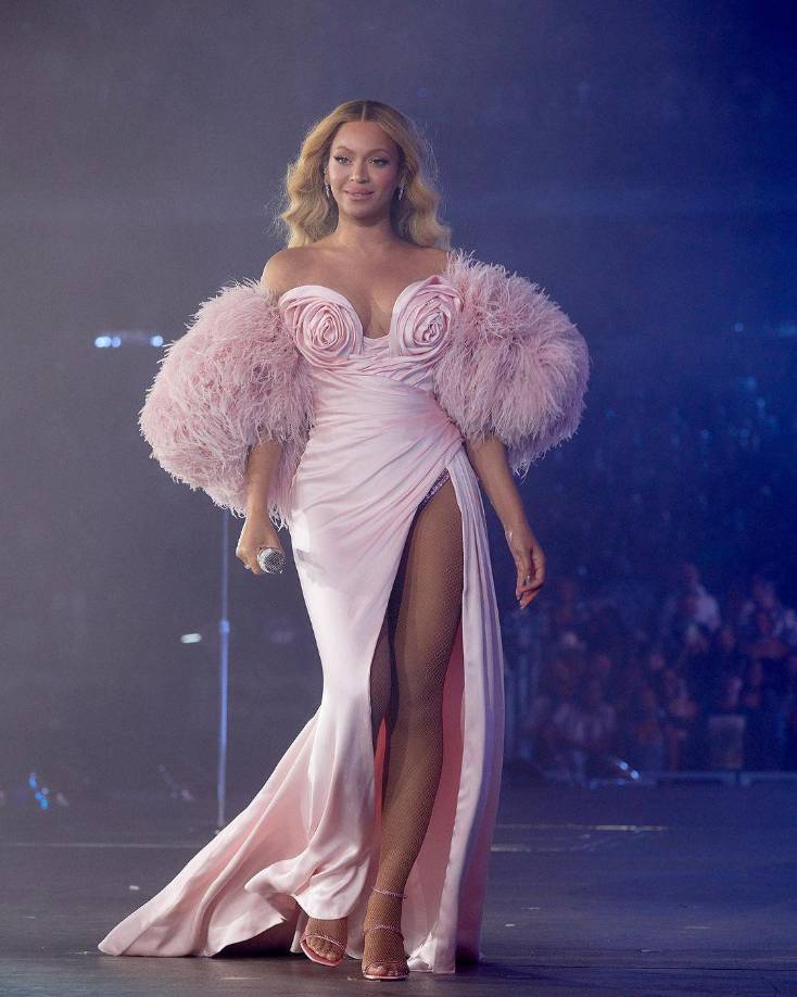 Beyoncé también ha lucido en múltiples ocasiones grandes atuendos muy femeninos en color rosa. Este fue uno de los más recientes en un concierto, la voluptuosa cantante resaltó su cuerpo con un vestido largo, de pierna abierta, con rosas en la parte del pecho y mangas de pelusa, dejando sus hombros al descubierto, toda una diva coqueta.