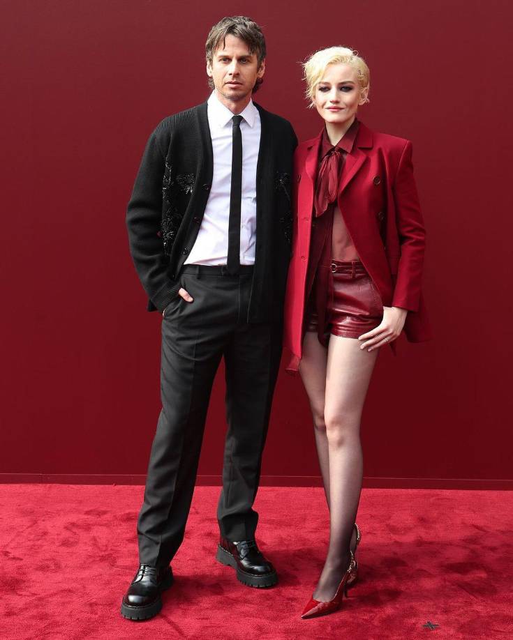 Julia Garner y su esposo Mark Foster se fueron combinados, ella espléndida en un conjunto de short, saco y blusa transparente en rojo y él en un tres piezas negro con jerséi.