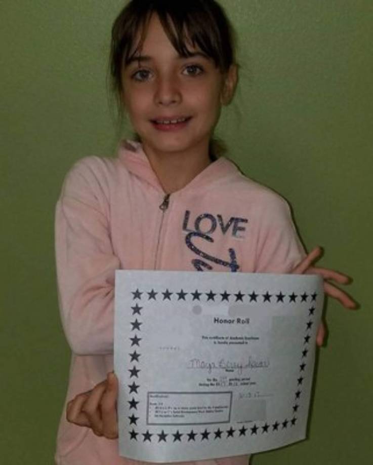 Maya mostrando su diploma que pertenece al cuadro de honor de su grado.