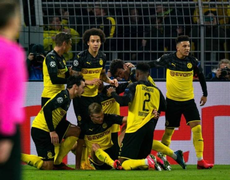 Dortmund's players pile on Dortmund's Norwegian forward Erling Braut Haaland after he scored the 2-1 goal during the UEFA Champions League Last 16, first-leg football match BVB Borussia Dortmund v Paris Saint-Germain (PSG) in Dortmund, western Germany, on February 18, 2020. (Photo by Sascha SCHÜRMANN / AFP)