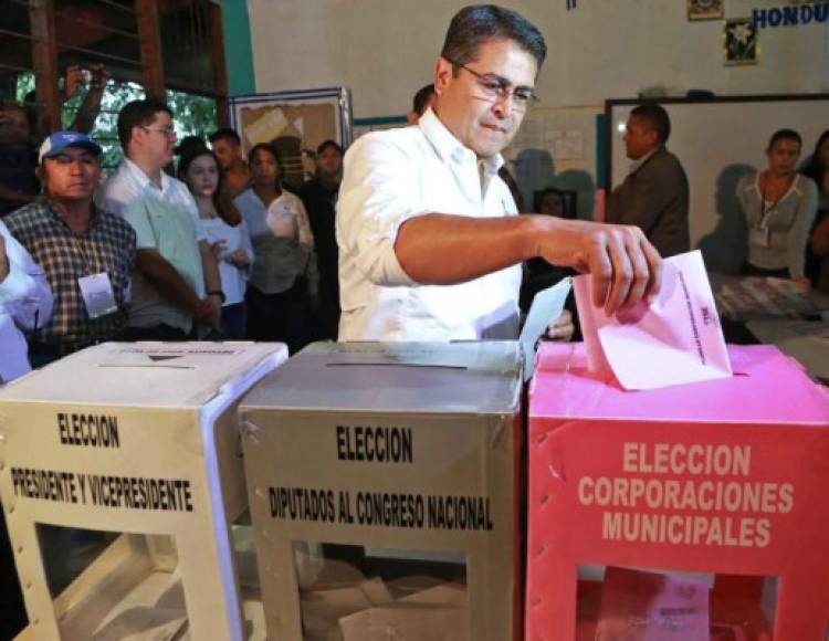 El presidente de Honduras, Juan Orlando Hernández, deposita una de las papeletas después marcarlas en el centro de votación.