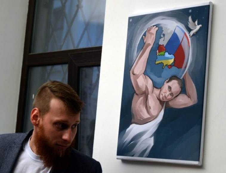 Un joven pasa frente a una pintura de Putin en un museo ruso, que exhibió diferentes retratos del mandatario, escenificando 'Los 12 trabajos de Putin'.