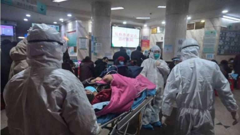 En esta foto tomada el 25 de enero de 2020, el personal médico de China usa ropa protectora para protegerse contra un coronavirus previamente desconocido. (Photo by Hector RETAMAL / AFP)