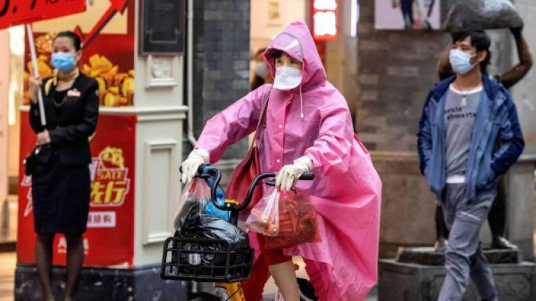 Una mujer con una mascarilla protectora monta una bicicleta en las calles de Guangzhou, provincia de Guangdong, China. Foto EFE